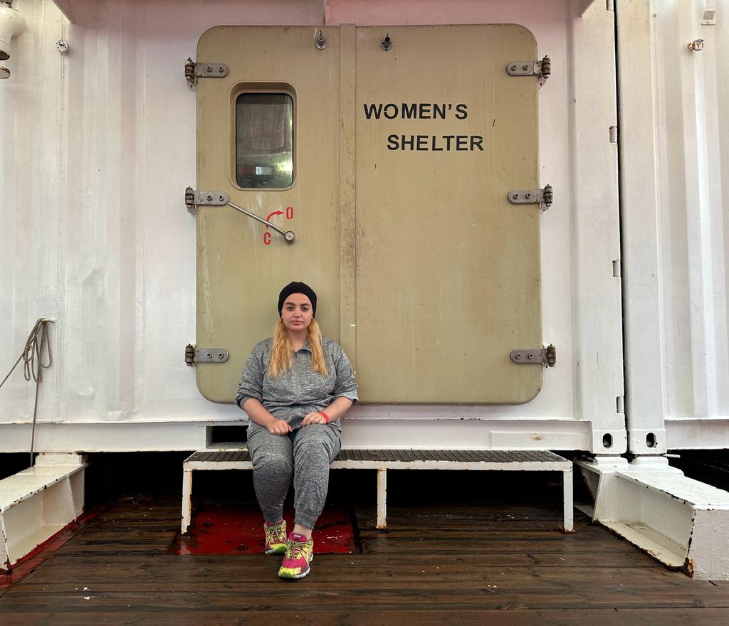 Marina sitzt vor der Tür zum Frauenschutzraum auf dem Schiff Ocean Viking